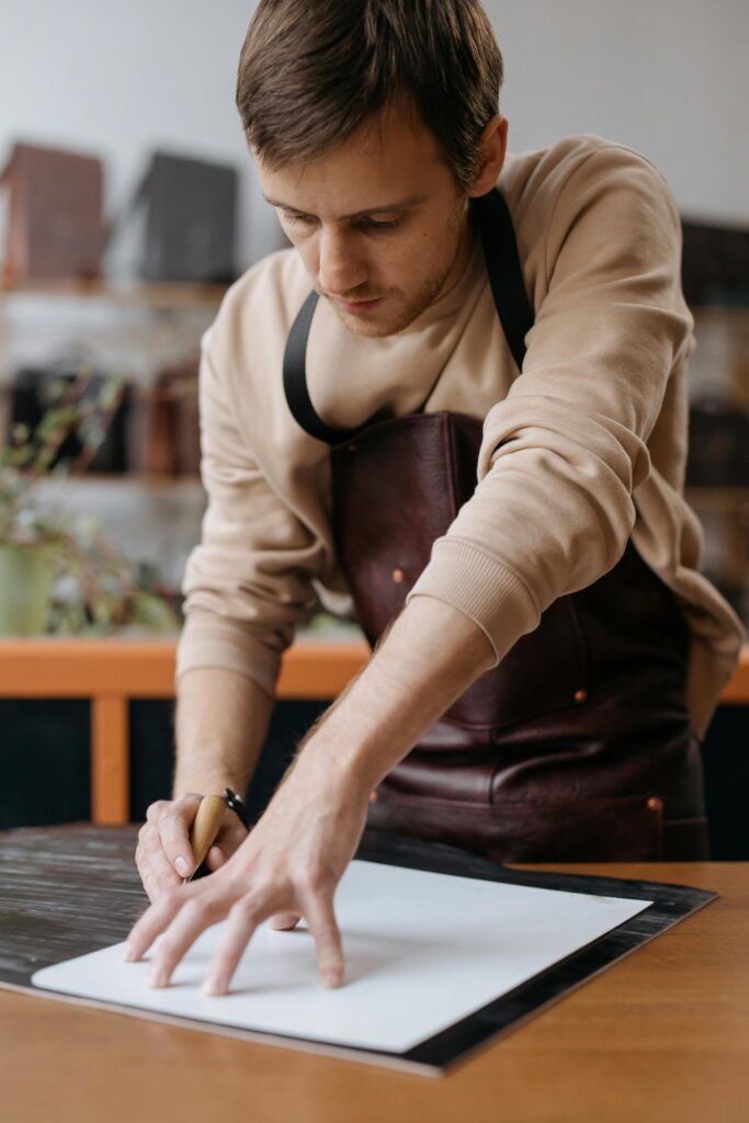 pexels-photo-6653998-6653998 Artisan focuses on crafting leather in a cozy workshop environment.